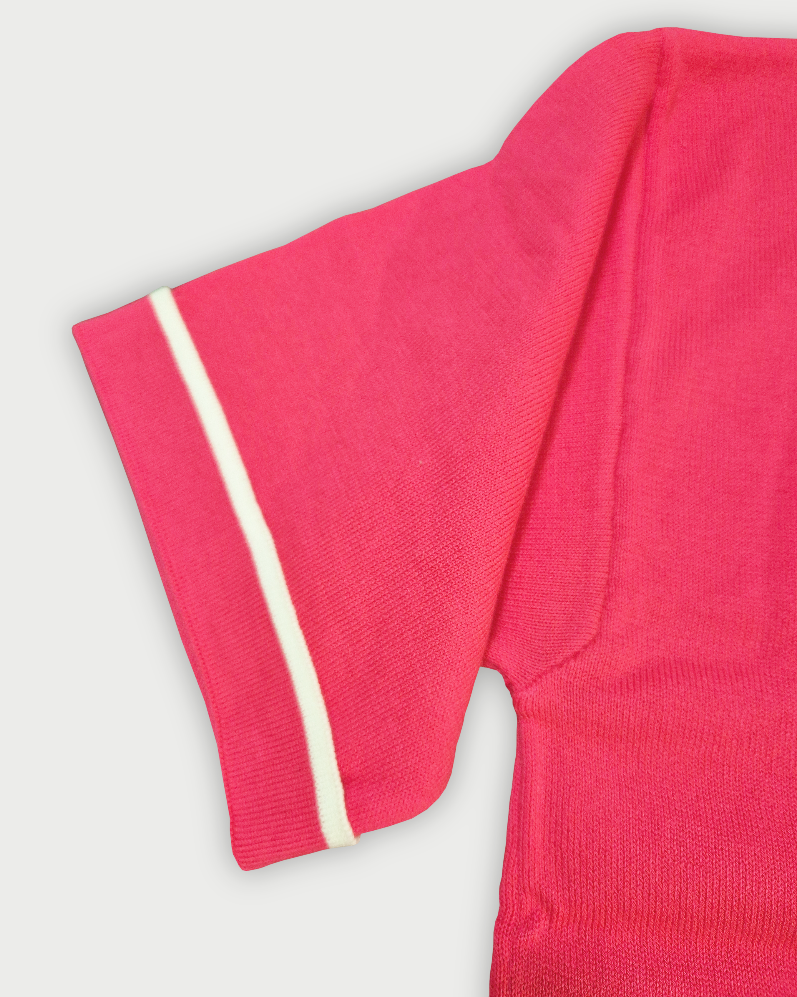 Dettaglio della manica con bordino bianco della maglia donna in maglia di cotone rosa corallo su sfondo bianco
