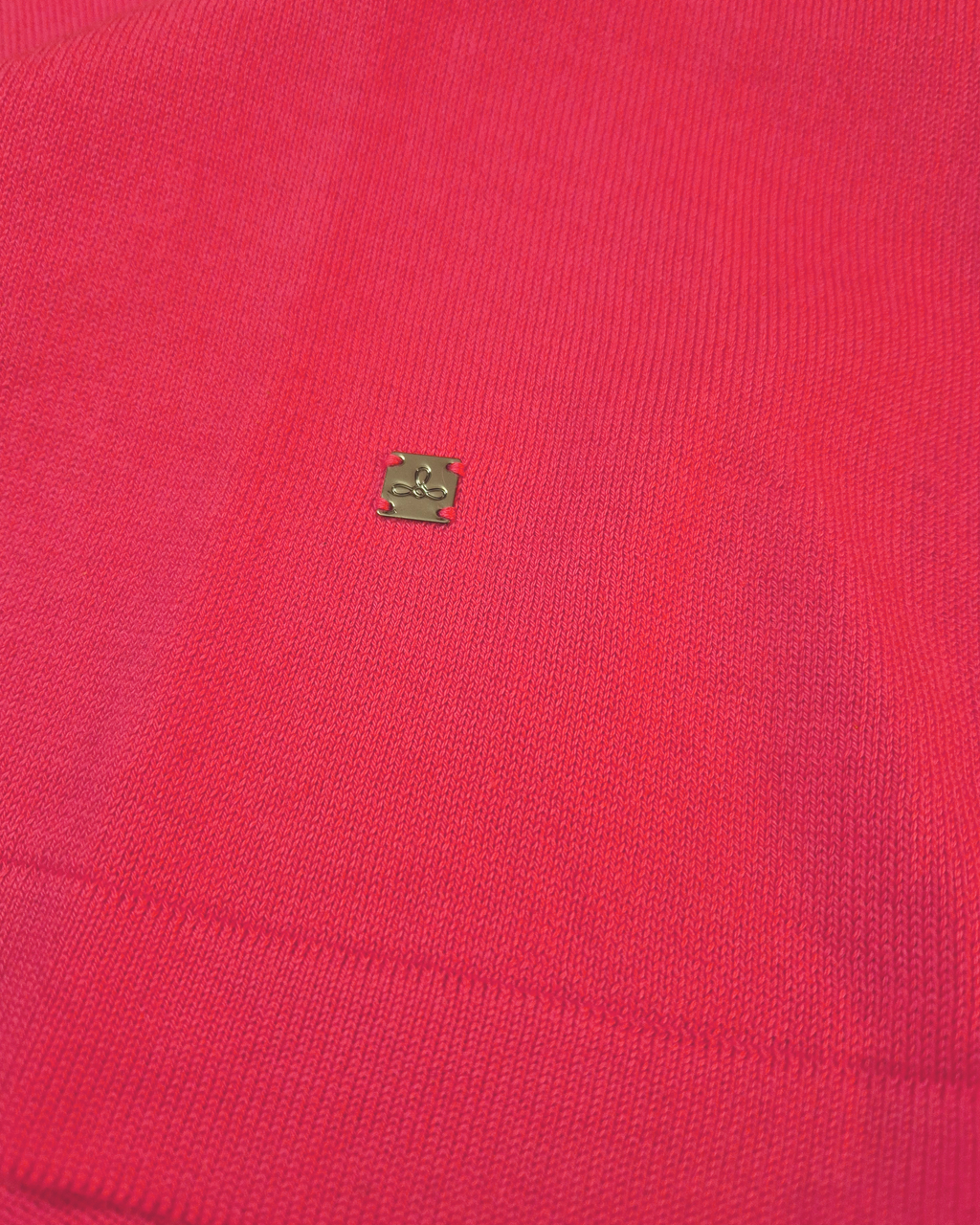 Dettaglio del logo Edua della polo donna over in maglia di cotone rosa corallo con colletto e bordi bianchi su sfondo bianco