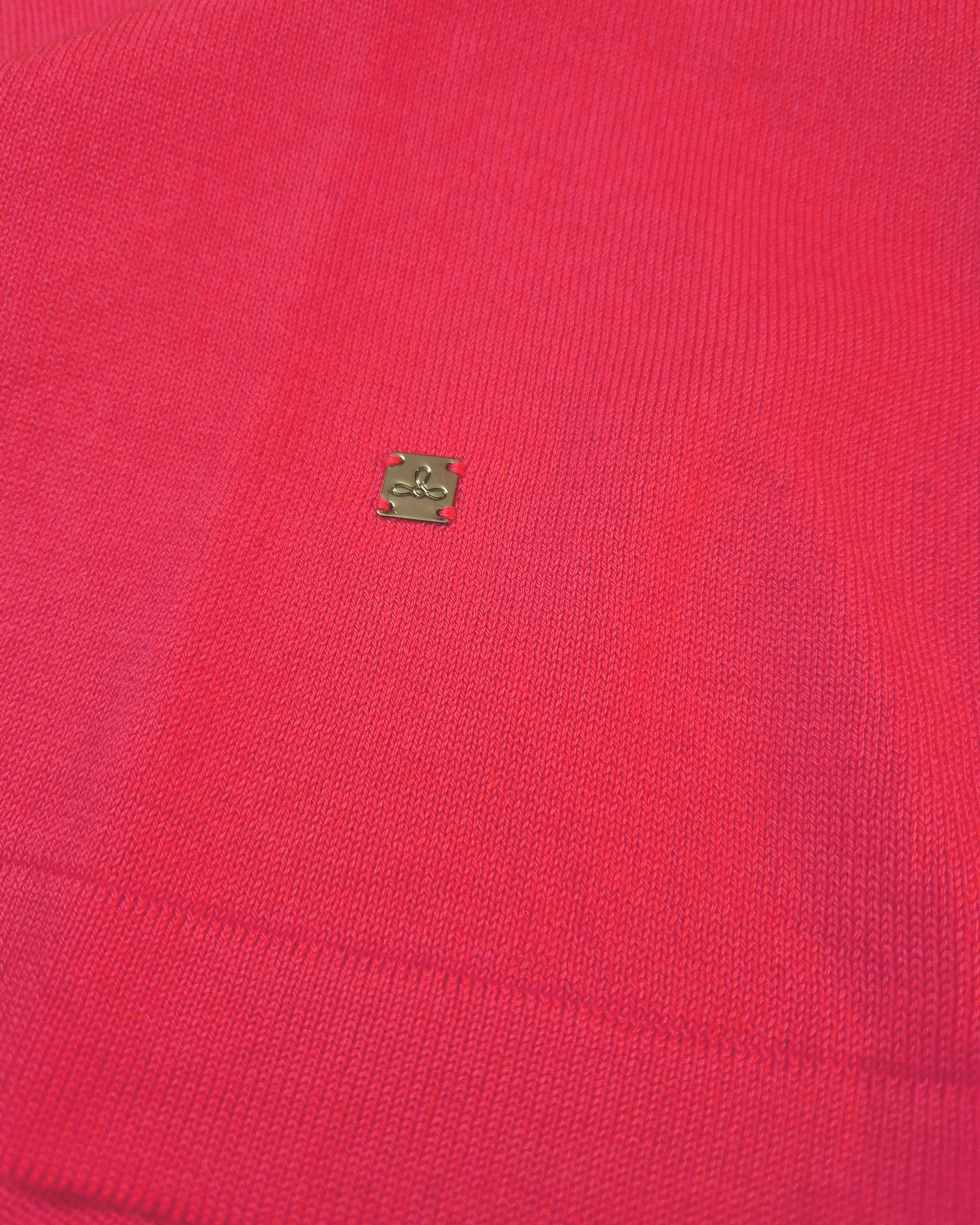 Dettaglio del logo Edua della polo donna over in maglia di cotone rosa corallo con colletto e bordi bianchi su sfondo bianco
