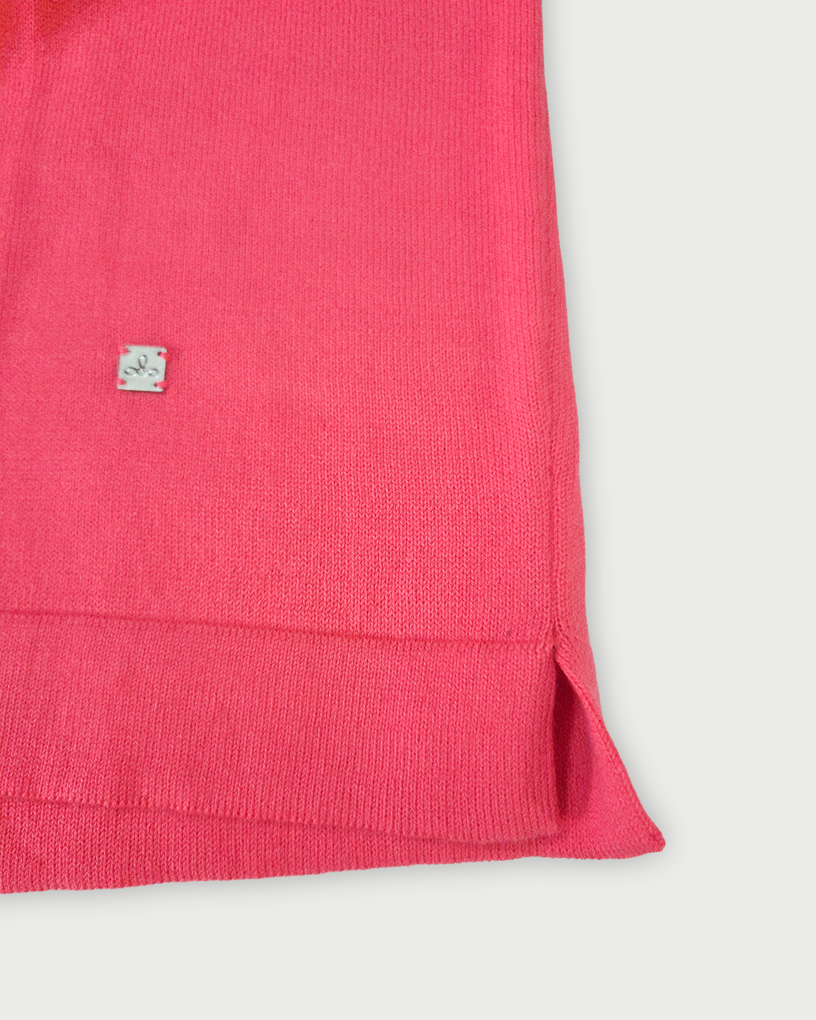 Dettaglio del fondo della maglia donna in cotone rosa corallo con scollo a V e profilo bianco su sfondo bianco