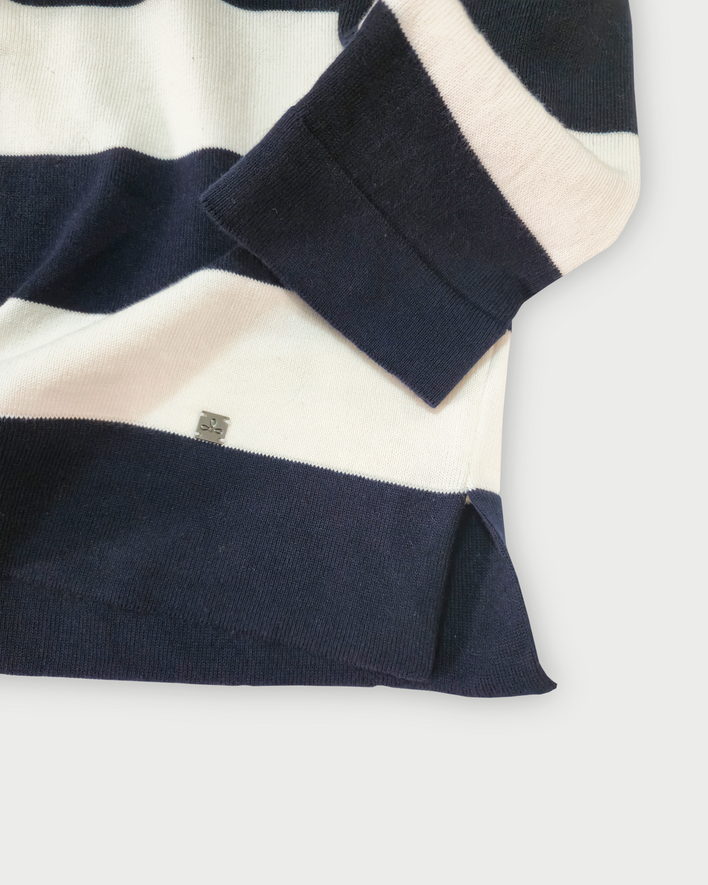 Dettaglio del fondo e del polsino della polo donna a righe blu e bianche in maglia di cotone