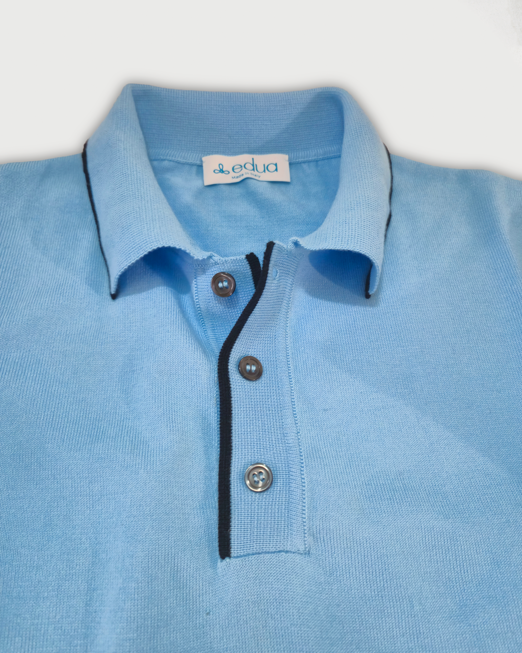 Dettaglio colletto polo uomo in maglia di cotone celeste su sfondo bianco