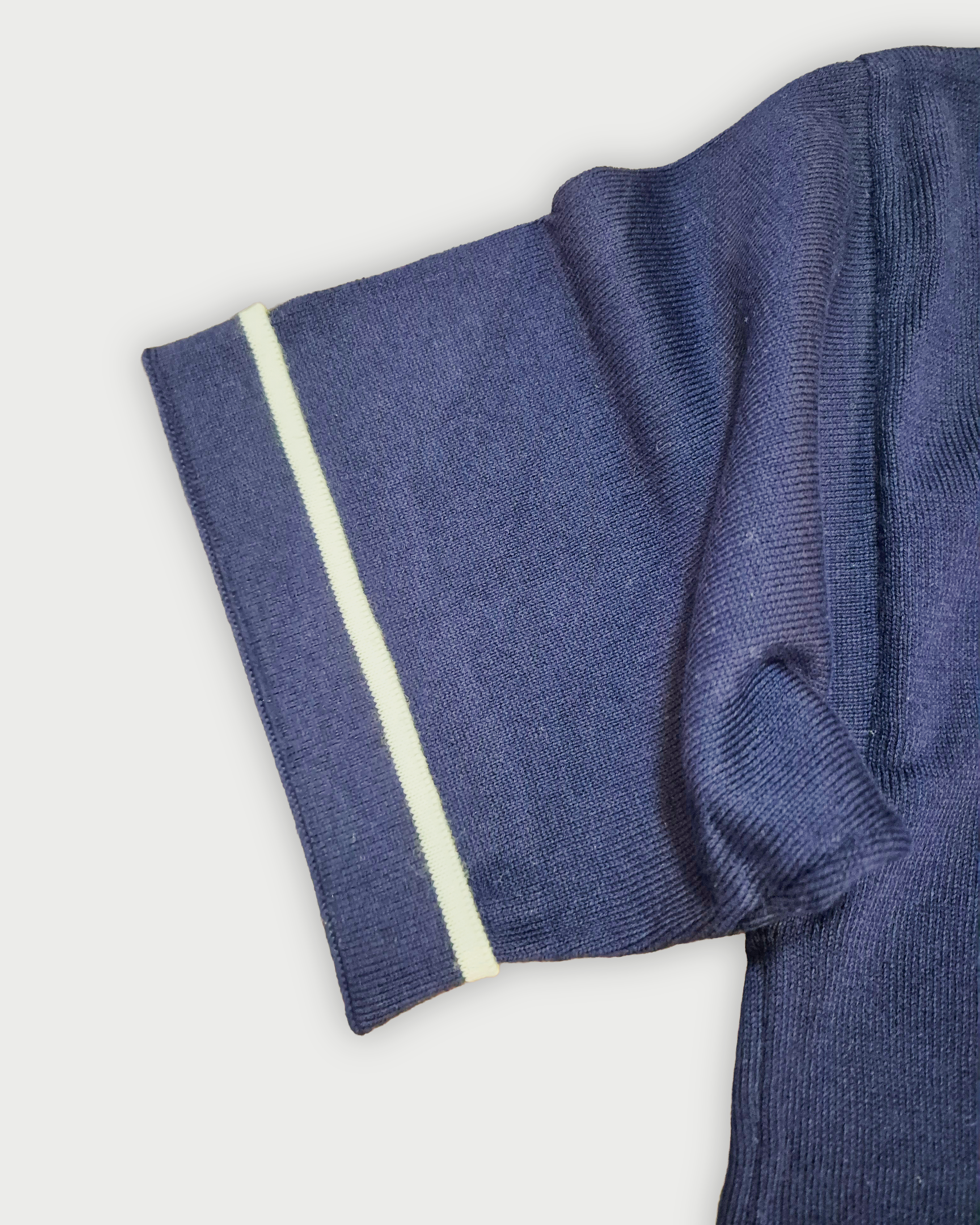 Dettaglio della manica con bordino bianco della polo donna over in maglia di cotone blu su sfondo bianco