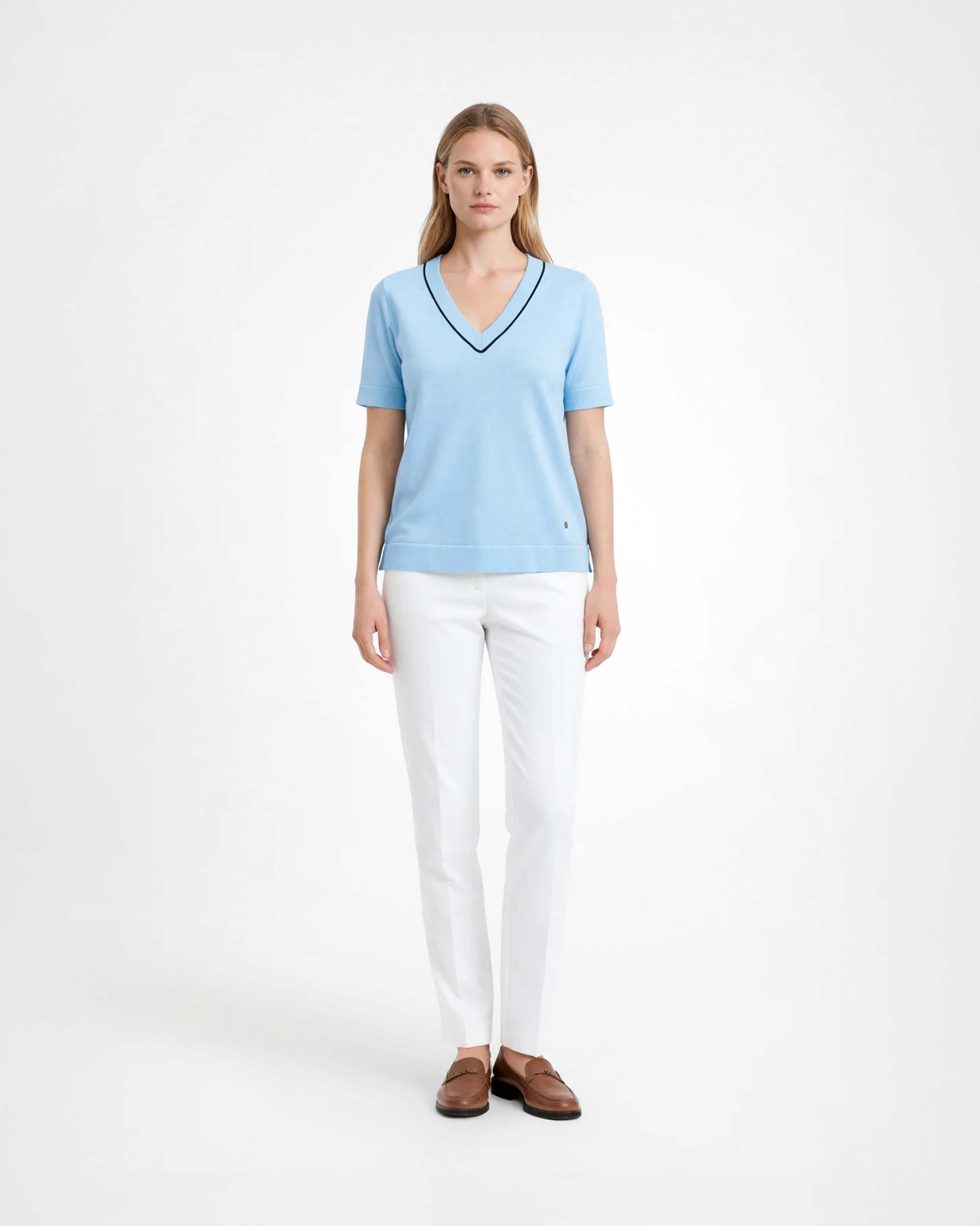 Maglia donna in maglia di cotone celeste con scollo a V e profilo blu indossata su sfondo bianco